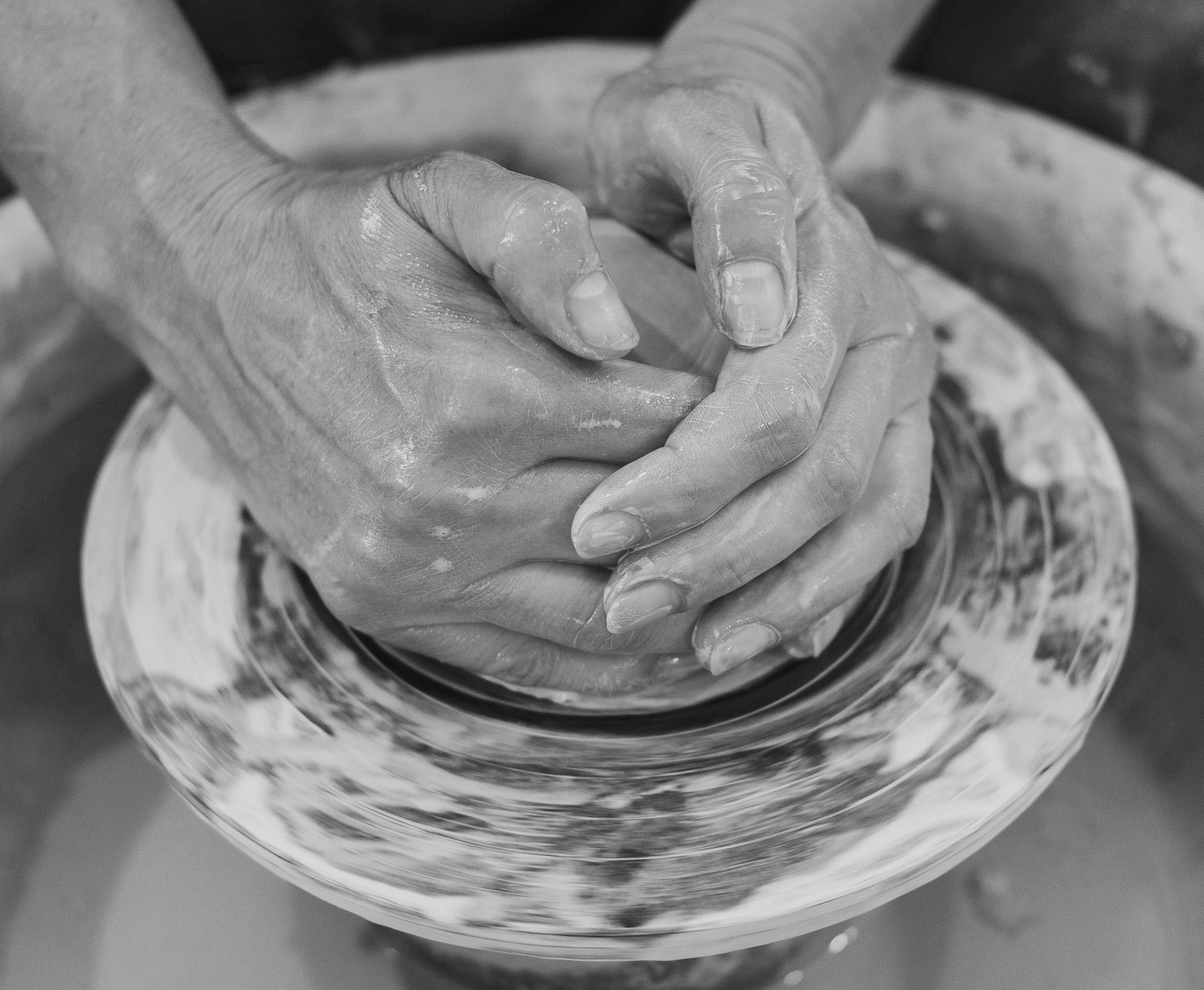 Hands shaping clay on a spinning pottery wheel